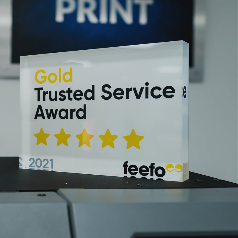 2021 'Gold Trusted Service Award' plaque from feefo on a table with a blurred background.