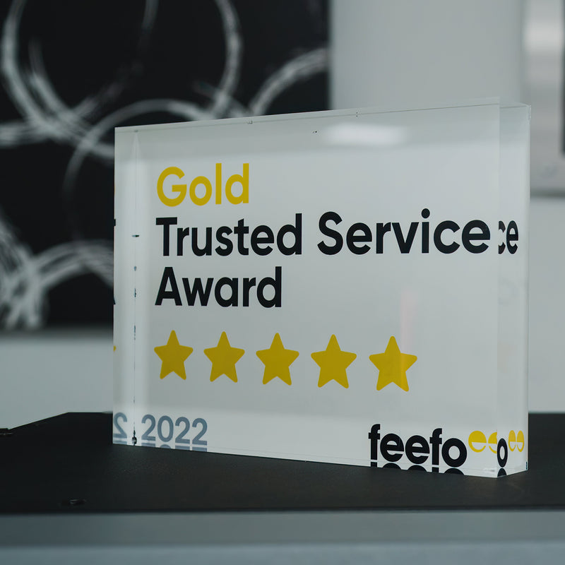 2022 'Gold Trusted Service Award' plaques from feefo on a table with a blurred background.